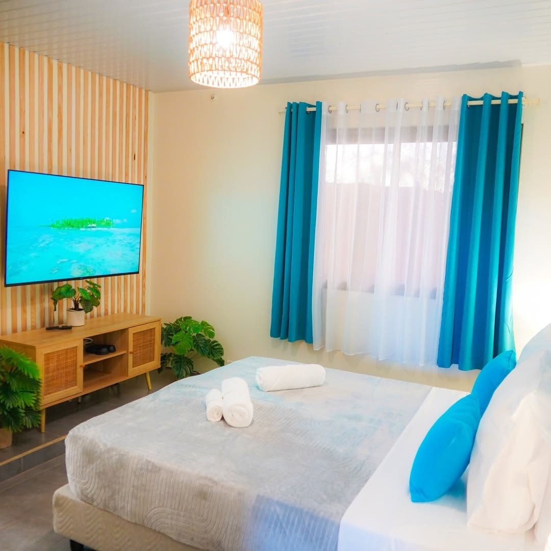 Chambre avec lit double, rideaux bleus et télévision murale